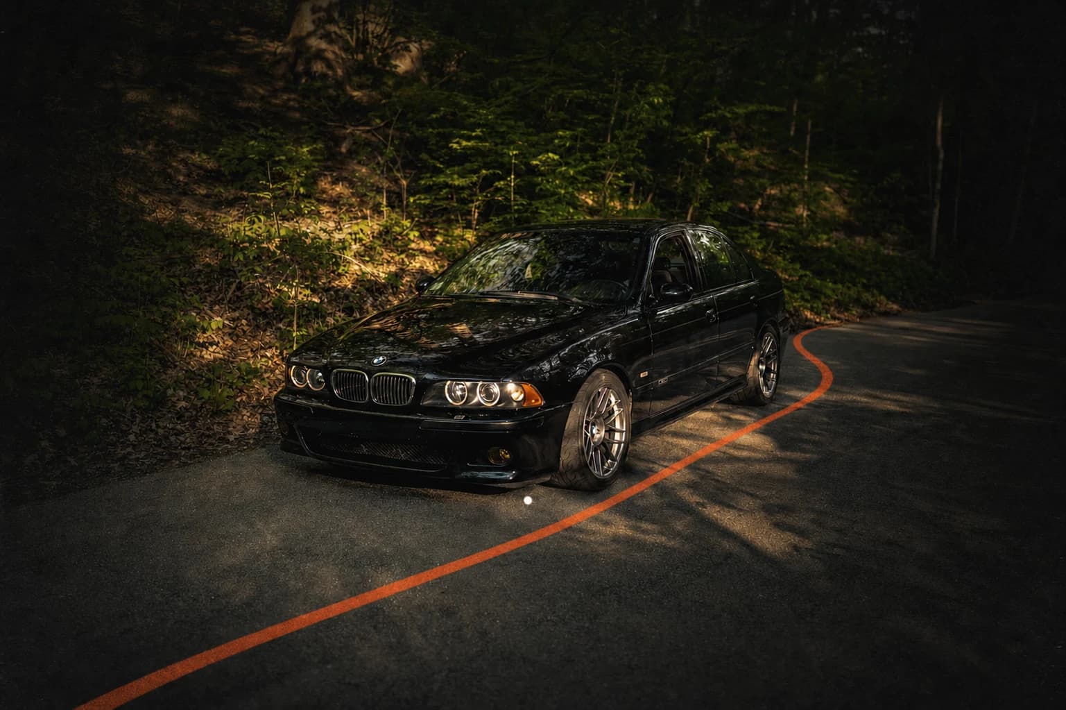Dark BMW E39 M5 on a wooded road
